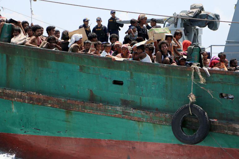 Navy officers look at migrants on their boat being towed away from Thailand by a Thai navy vessel, in waters near Koh Lipe island May 16, 2015. Malaysian vessels on Saturday intercepted a boat crammed with migrants after the Thai navy towed it away from T