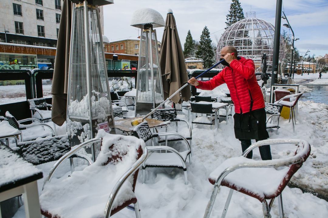 El propietario de un bar limpia su terraza tras el paso del temporal Filomena en Soria