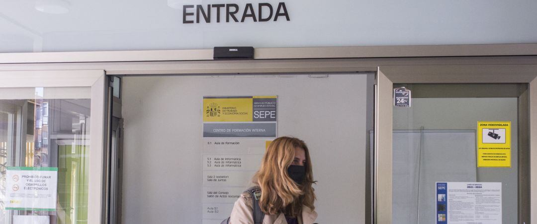 Una mujer entra por la puerta de una oficina del SEPE.