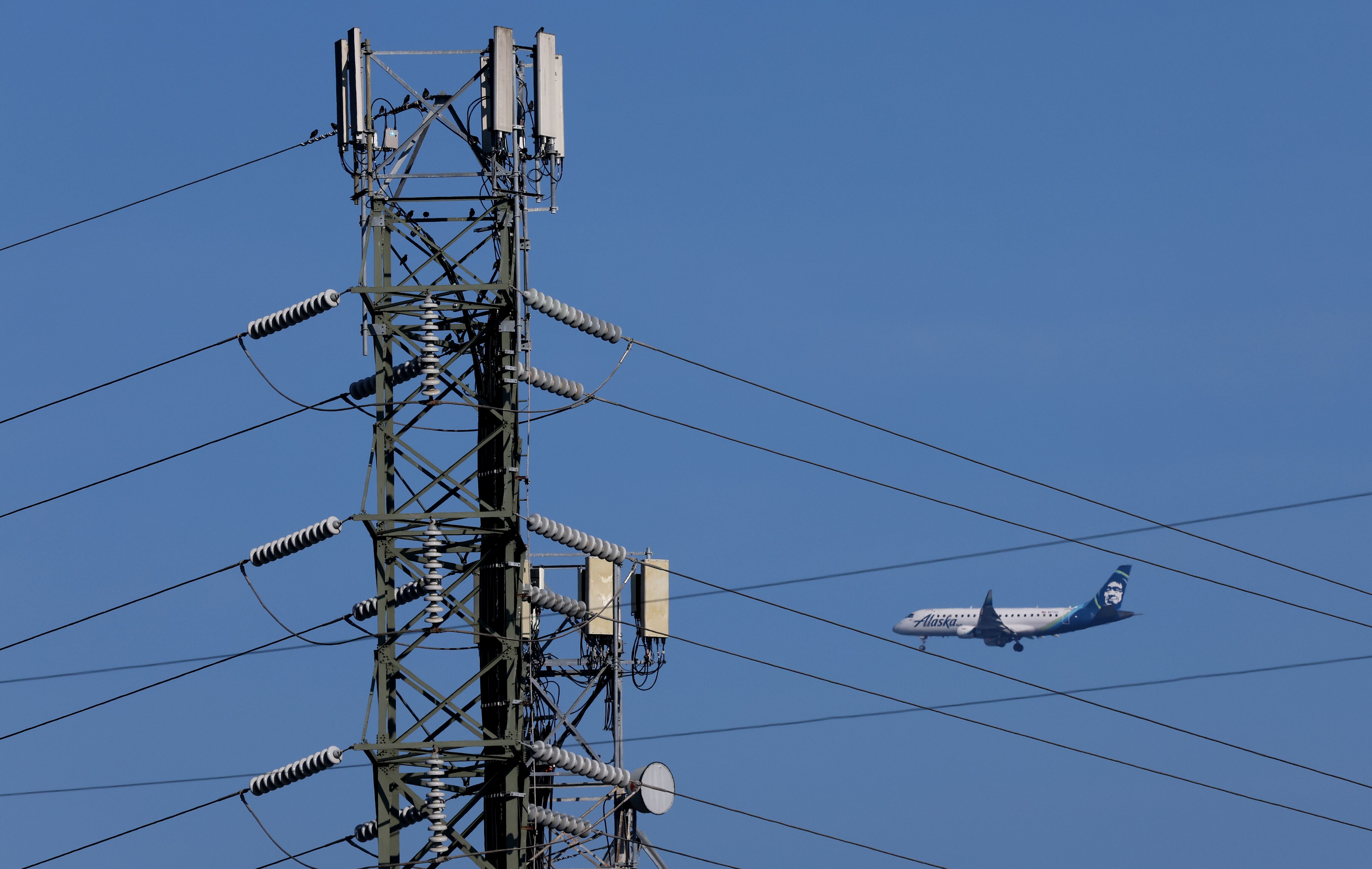 SAN MATEO, CALIFORNIA - JANUARY 18: An Alaska Airlines plane flies by a cellular tower as it prepares to land at San Francisco International Airport on January 19, 2022 in San Mateo, California. Verizon and AT&T announced that they will proceed with plans to activate 5G cellular service across the nation on Wednesday with the exception of near airports and runways after the Federal Aviation Administration and major airlines warned that the signal could interfere with navigational systems on some planes and cause flight disruptions. (Photo by Justin Sullivan/Getty Images)