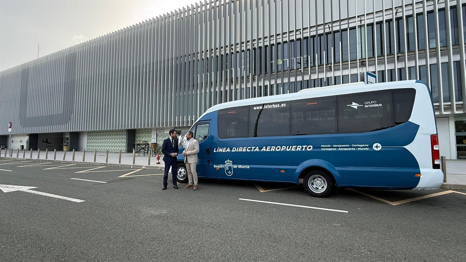 El director general de Movilidad y Transportes, José Antonio Verdú y el director general del Aeropuerto Internacional Región de Murcia, Carlos San Martín, junto a uno de los autobuses que realiza la conexión del aeropuerto con Murcia y Cartagena
