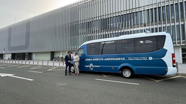 El director general de Movilidad y Transportes, José Antonio Verdú y el director general del Aeropuerto Internacional Región de Murcia, Carlos San Martín, junto a uno de los autobuses que realiza la conexión del aeropuerto con Murcia y Cartagena