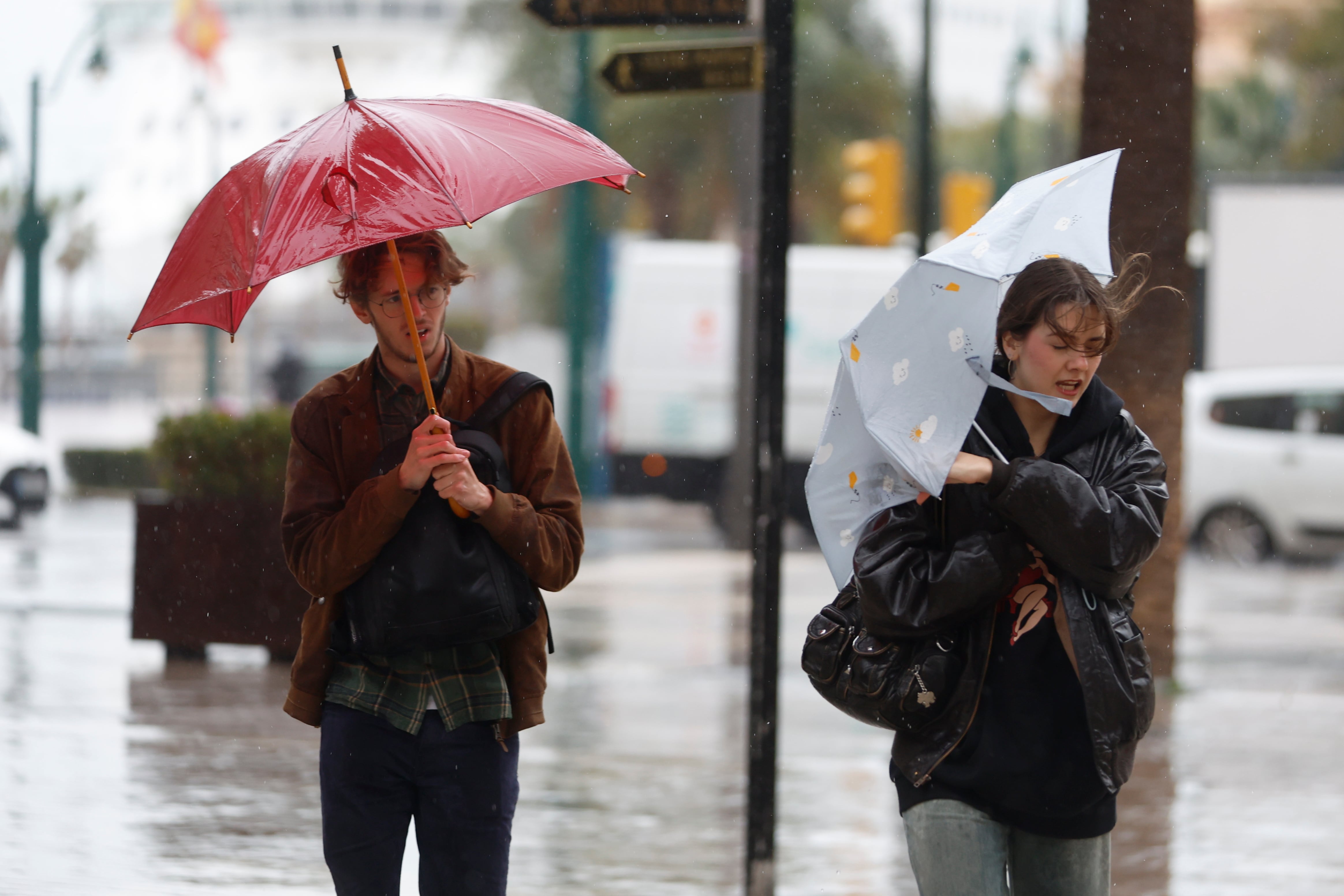 MÁLAGA, 28/01/2026.- Varias personas luchan contra el fuerte viento que se registra este miércoles en Málaga. La borrasca Kristin complica este miércoles la jornada meteorológica en Andalucía, donde las clases están suspendidas en 77 municipios de la comunidad, con aviso rojo por viento en Valle del Almanzora y Los Vélez en Almería, y naranjas y amarillos por viento, lluvia y fenómenos costeros en el resto. EFE/ Jorge Zapata