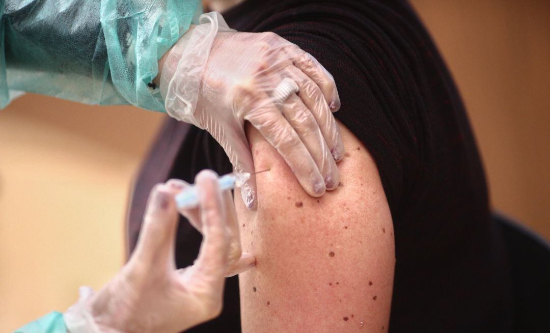 Una profesional farmacéutica recibe la vacuna contra la COVID-19.