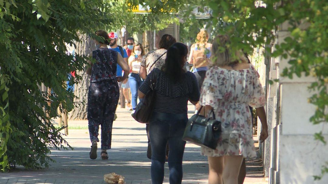 Los ciudadanos, protegidos con sus mascarillas, hacen frente al calor en las calles. 