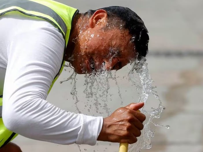 Un trabajador combate el calor mojándose la cabeza