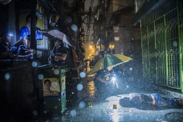 Fotografía cedida por The New York Times del fotógrafo colaborador Daniel Berehulak que muestra a policías detallando el cuerpo de Romeo Torres Fontanilla, muerto a tiros por dos desconocidos en el distrito de Pasay, Manila, Filipinas