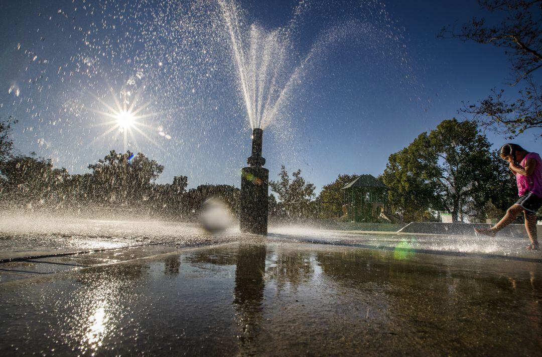 Una niña juega en una fuente en plena ola de calor.