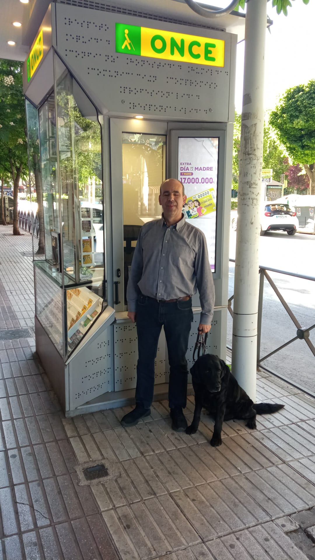 Miguel Ángel López, con Ator frente a su kiosco de la ONCE en Puertollano