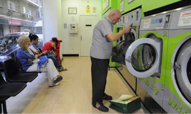 Un cliente pone la lavadora mientras otros tres esperan a que su colada termine