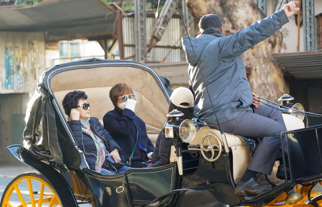 Turistas en coche de caballos en Sevilla paseando con mascarillas