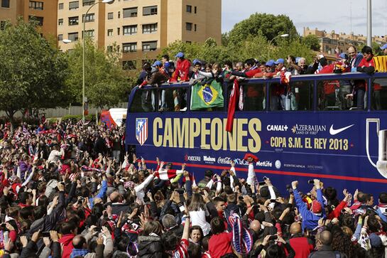 Los jugadores y componentes del cuerpo técnico del Atlético de Madrid subidos en autobús descapotable, parten desde el estadio Vicente Calderón en el recorrido que realizan por las calles