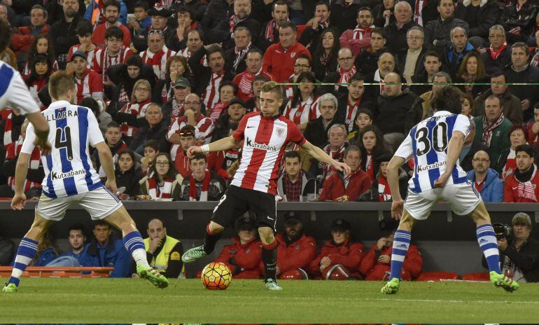 El delantero del Athletic de Bilbao Iker Muniain (c) entre el centrocampista Asier Illarramendi (i) y el defensa Aritz Elustondo (d), de la Real Sociedad, durante el partido de la vigésimo quinta jornada de la Liga de Primera División disputado en el esta