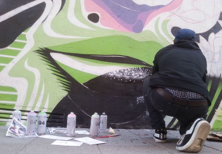 El artista Dourone pintando el mural en la calle Valverde