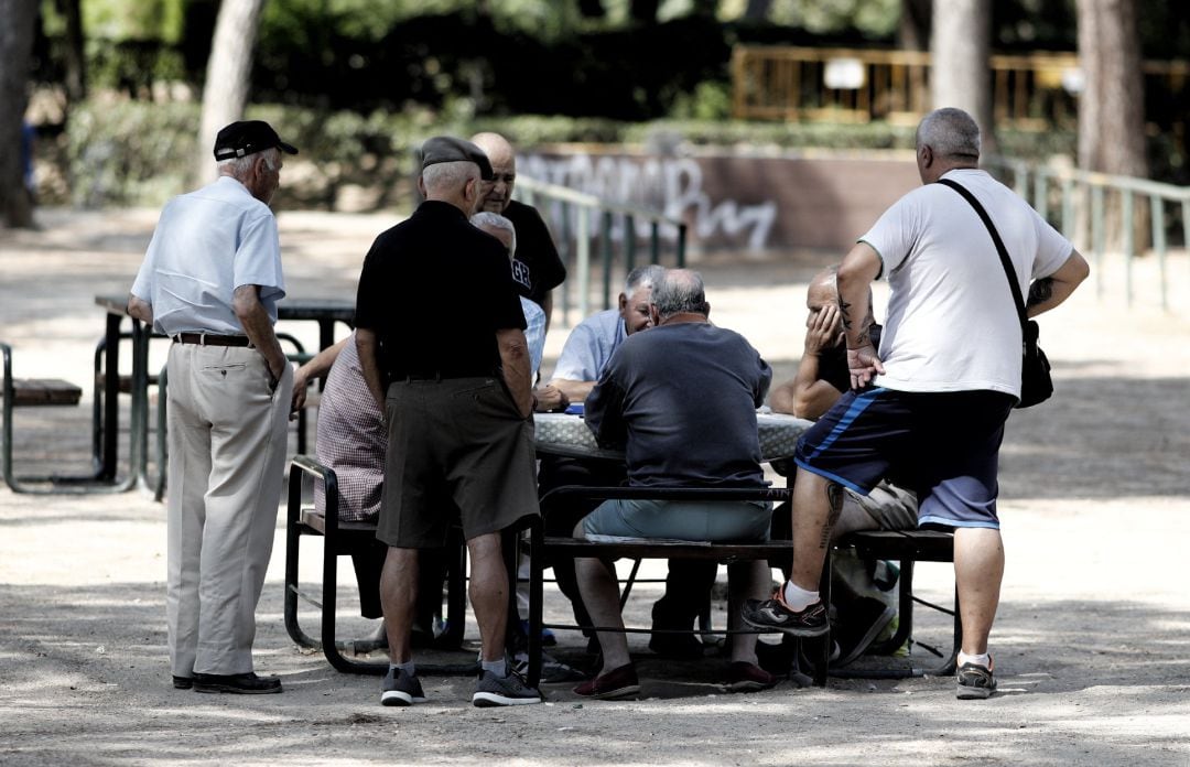 Varios pensionistas juegan al dominó en un parque de Madrid.