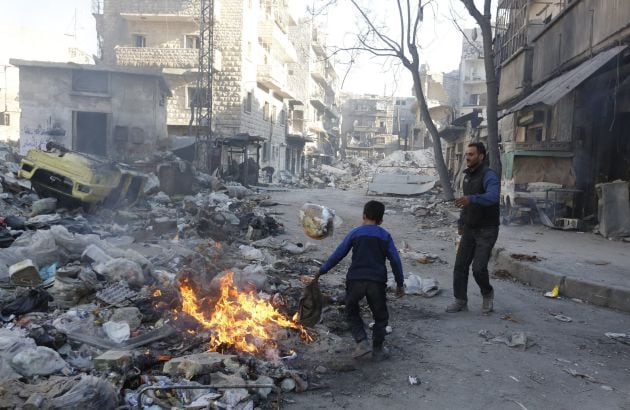 Un niño enciende una fogata en el barrio Bustan Alqasr en Alepo (Siria)