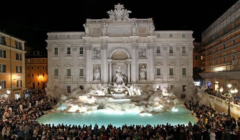 Varias personas observan la Fontana de Trevi iluminada.