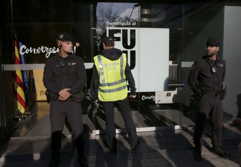 BARCELONA, 21/10/2015.- Agentes de la Guardia Civil ante la fachada de la sede de CDC en Barcelona que esta siendo registrada.