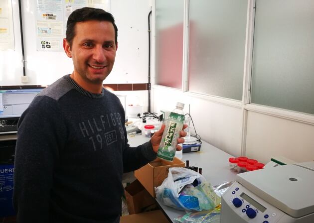 Javier Hernández, profesor de Química Analítica de la Universidad de La Laguna, sostiene una botella de procedencia asiática que forma parte de la basura marina detectada en la Playa del Ámbar, en La Graciosa