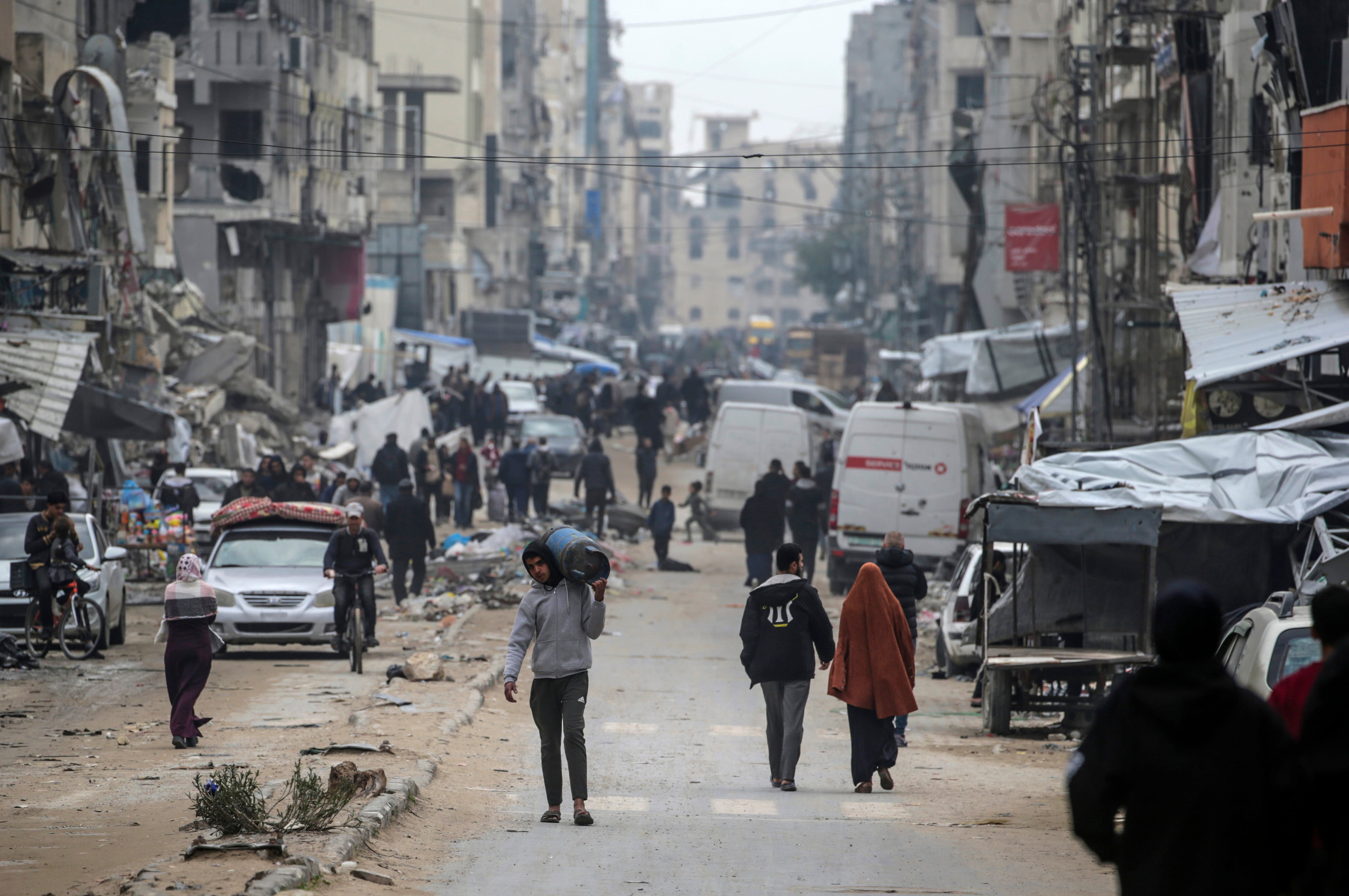 Palestinos caminando por la ciudad de Gaza entre las ruinas que han dejado el bombardeo israelí