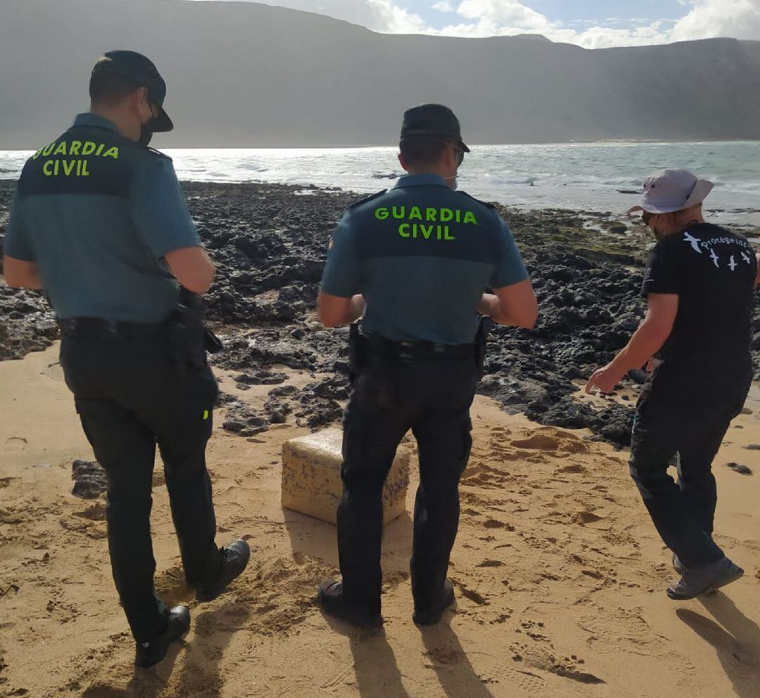 Agentes de la Guardia Civil y el vecino que encontró la droga, junto al fardo de hachís.