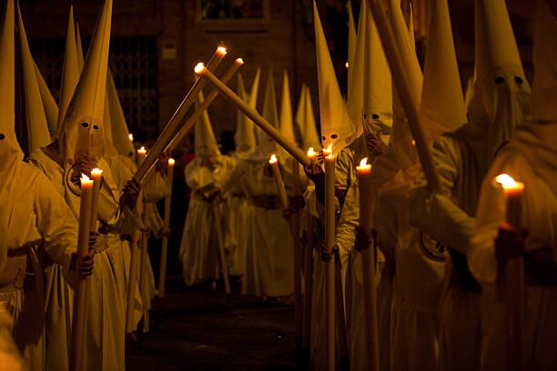 Processions of Nazarenos walk the streets at night during Semana Santa in Sevilla, Spain.