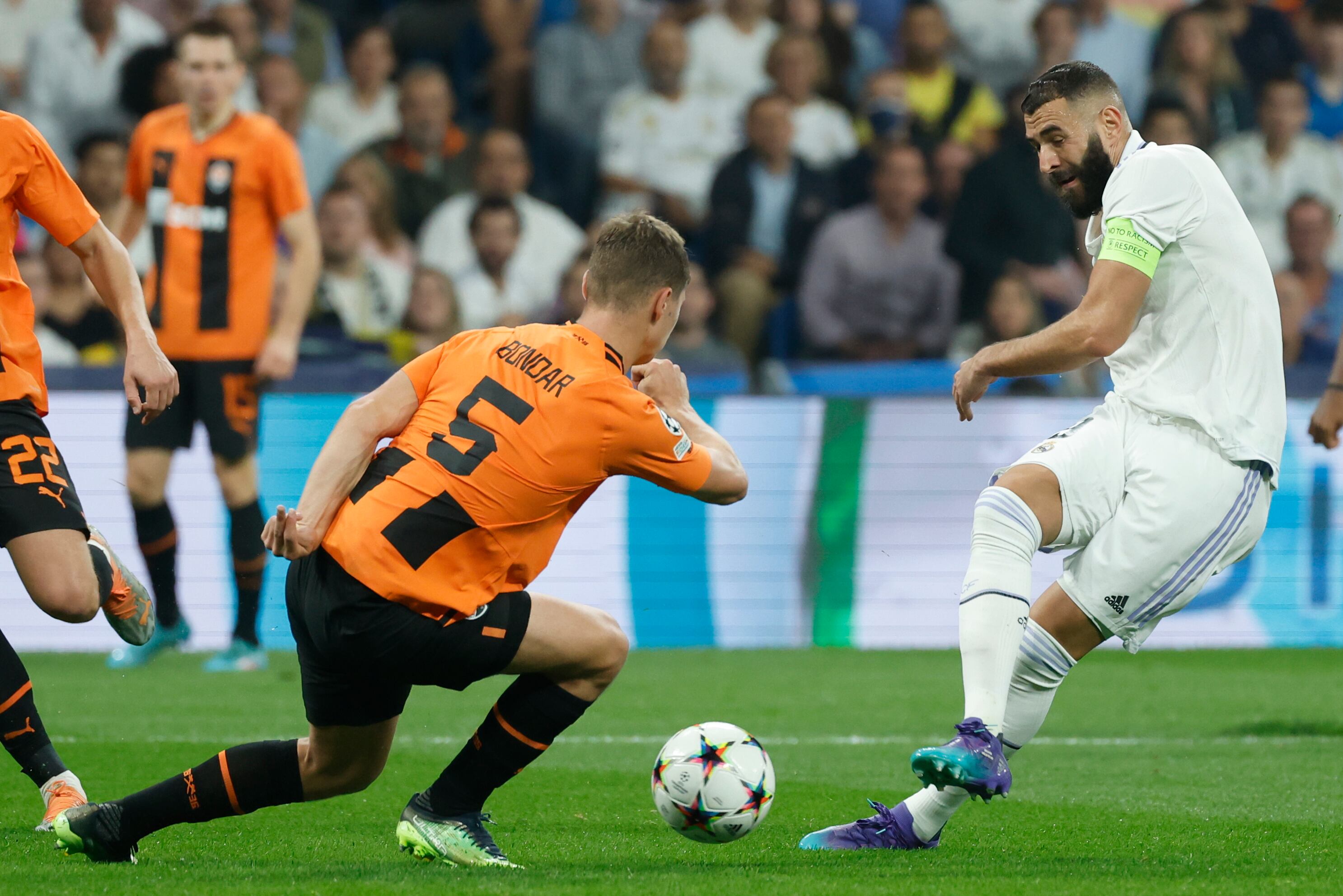 El delantero del Real Madrid Karim Benzema (d) dispara ante Valeriy Bondar (i), del Shakhtar Donetsk.