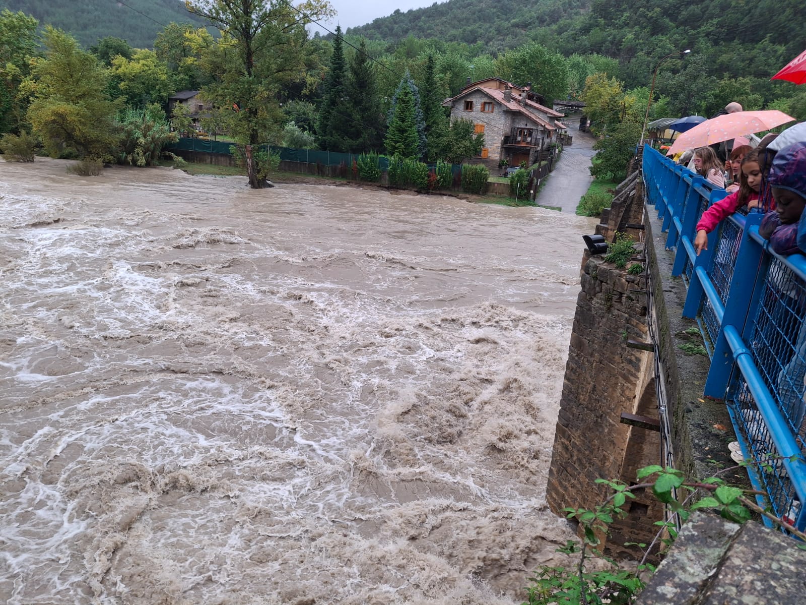 Vecinos y visitantes ven la crecida en el río Ara a su paso por Boltaña. EVA SÁNCHEZ