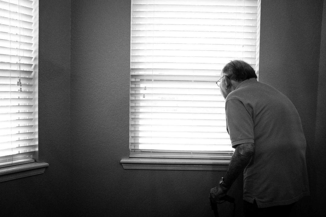 Un anciano contempla el exterior de su casa desde su ventana