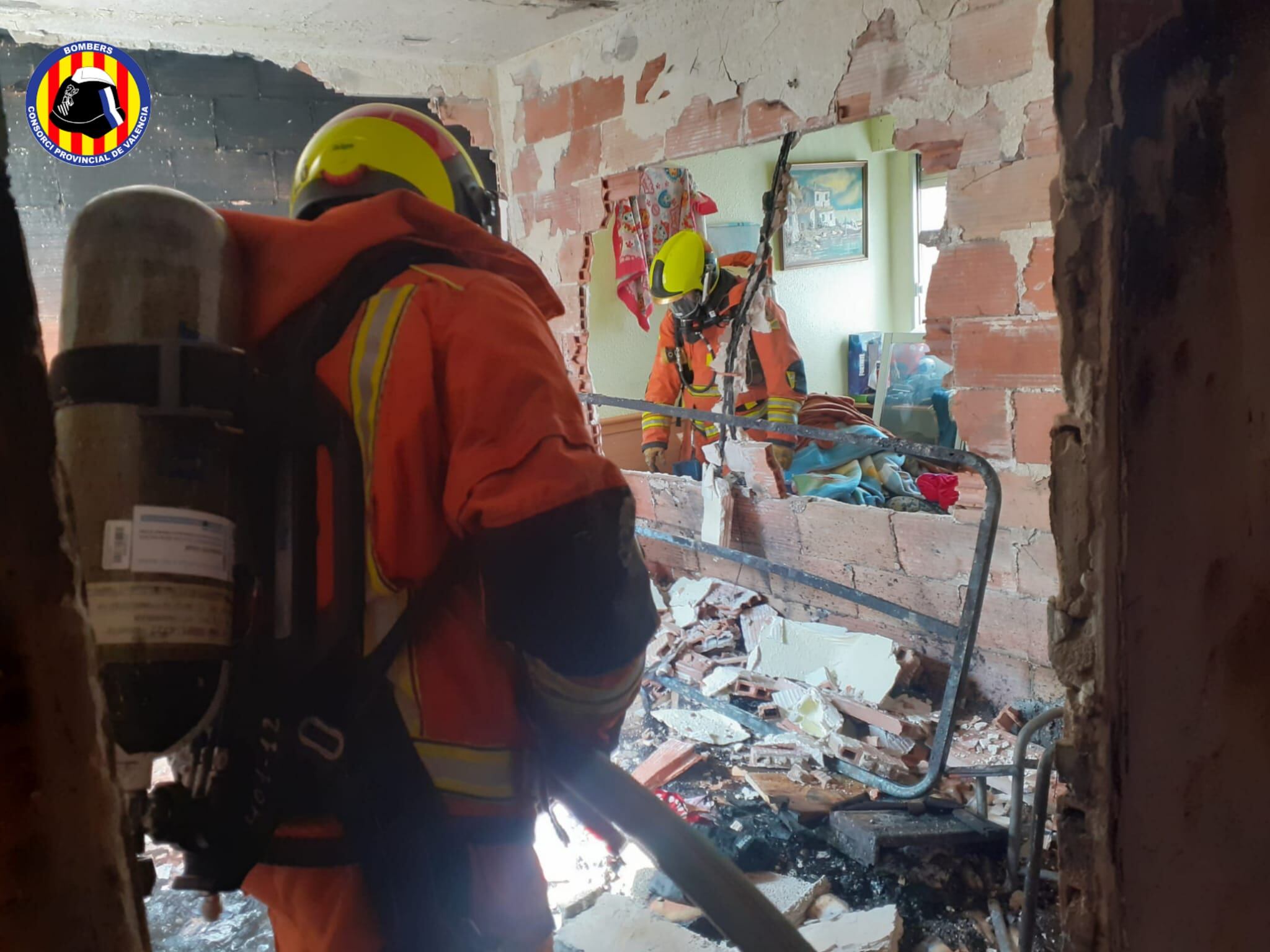Bomberos inspeccionan la vivienda calcinada en Benifairó de la Valldigna.