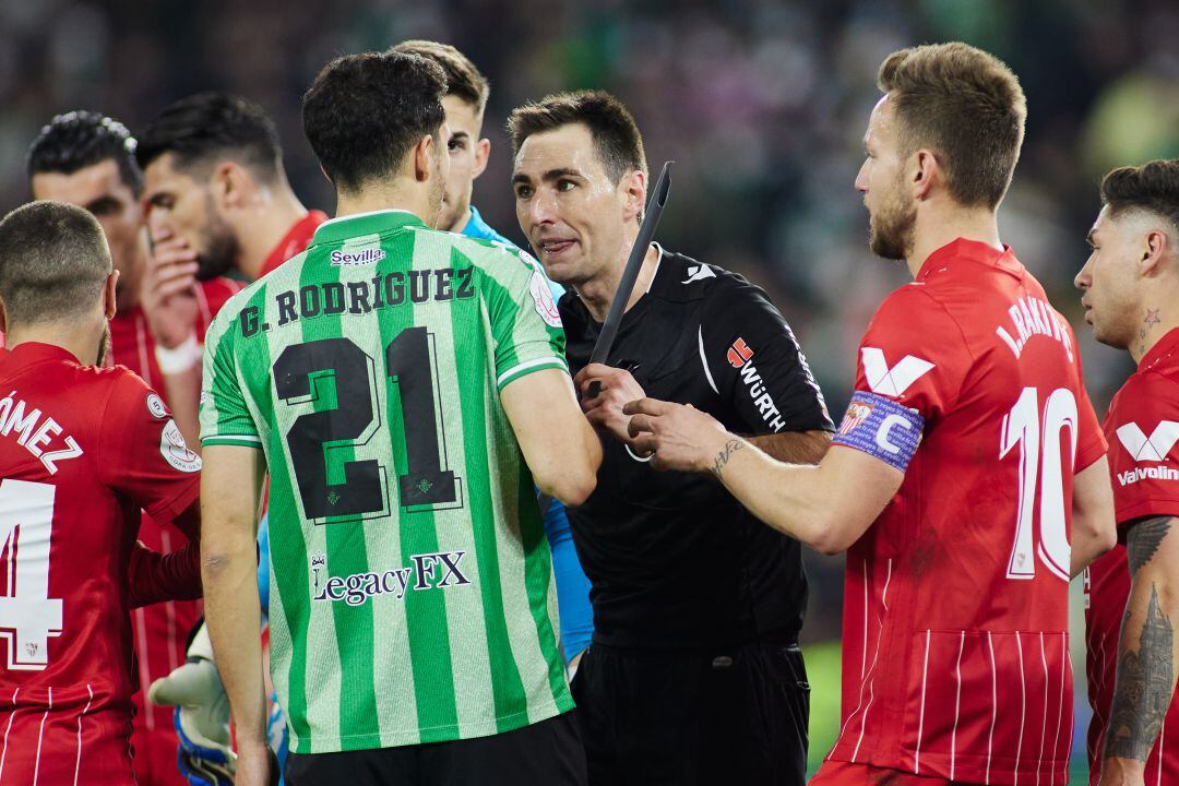 Guido Rodríguez y Rakitic conversan con el árbitro tras el lanzamiento del palo que alcanzó a Joan Jordán. 