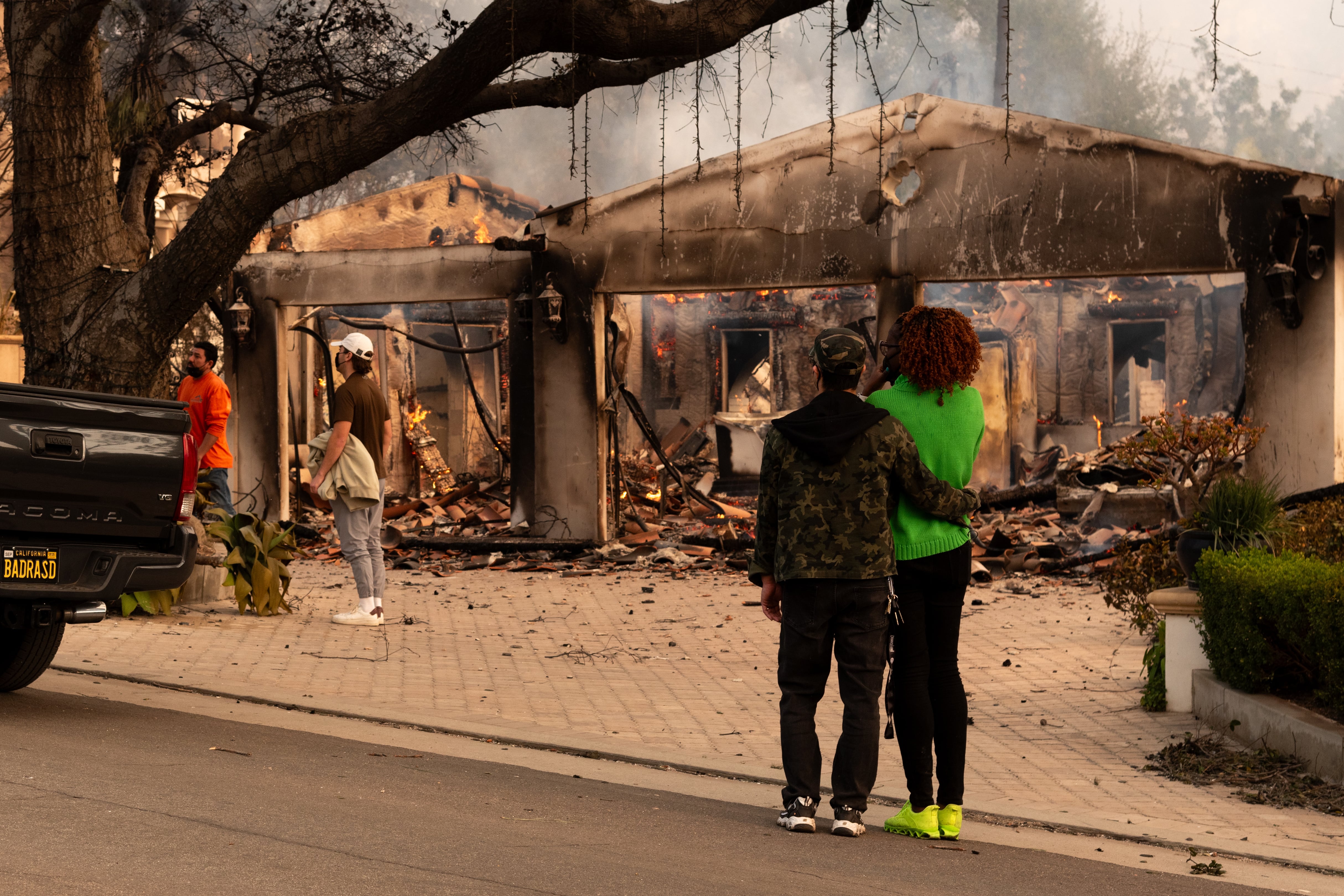 Personas observan una casa afectada por un incendio este miércoles, en Altadena, California (Estados Unidos). 