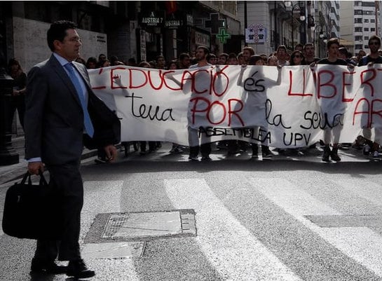 Miles de estudiantes se han manifestado esta mañana en Valencia contra los recortes y la denominada &quot;ley Wert&quot;, Ley de mejora de la calidad educativa (Lomce). En la imagen, un hombre pasa ante una de las pancartas de la manifestación.