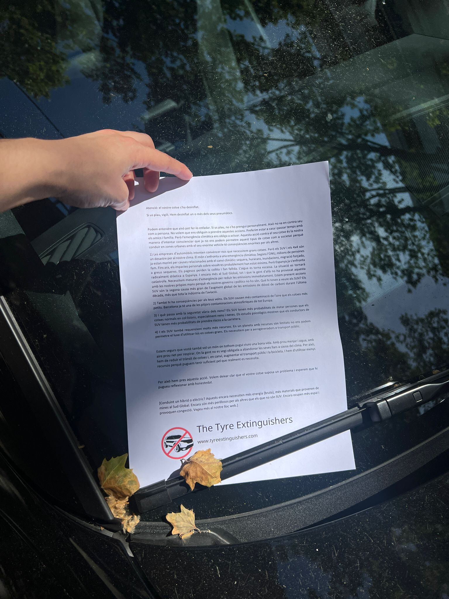 Carta reivindicativa al parabrisa d'un cotxe amb la roda desinflada