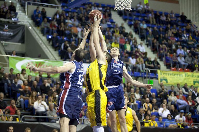 El pivot montenegrino del Iberostar Tenerife, Blagota Sekulic (c), disputa un rebote ante los jugadores del Rio Natura, el estadounidense Aleksandar Maric (i) y el alero lituano, Eimantas Bendzius, durante el encuentro correspondiente a la jornada de liga