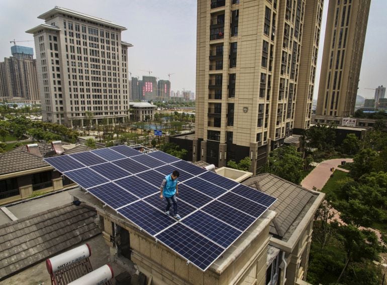 Un trabajador instala paneles solares en un tejado de un edificio. 