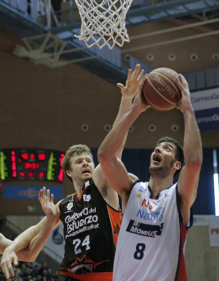 El jugador del Obradoiro Juanjo Triguero (d) entra a canasta ante la oposición del jugador del Valencia Basket, John Shurna, durante el encuentro de la jornada 25 de la fase regular de la liga ACB disputado en el Multiusos de Sar de Santiago de Compostela