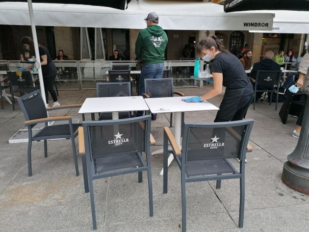 Una camarera desinfecta la mesa de una terraza de la plaza del Castillo