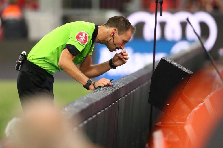 Un árbitro revisa una jugada en un partido de la Bundesliga.