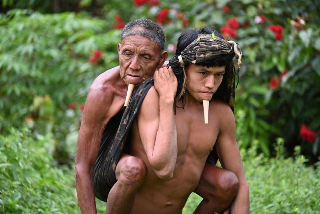 Un hijo carga a su padre para que pueda vacunarse.