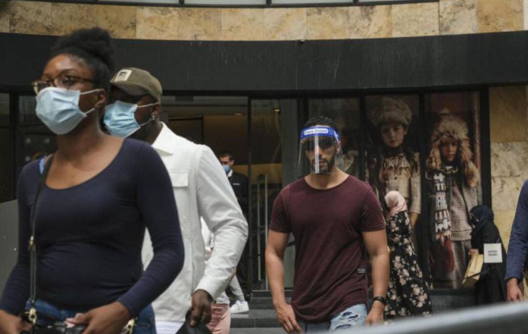 Viandantes pasean por una ciudad con mascarillas y protección facial