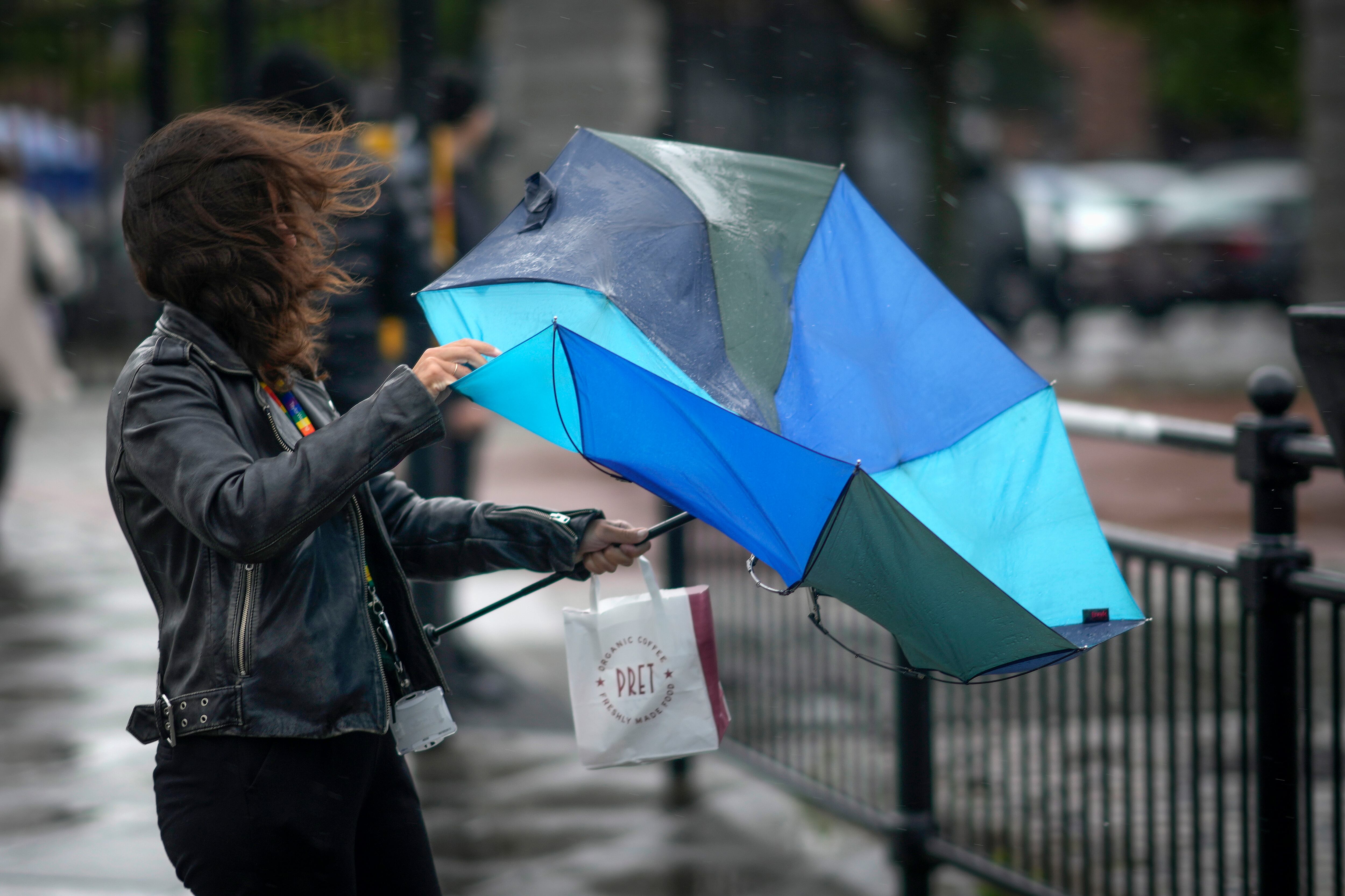 Una mujer intenta hacerse con el paraguas. (Photo by Christopher Furlong/Getty Images)