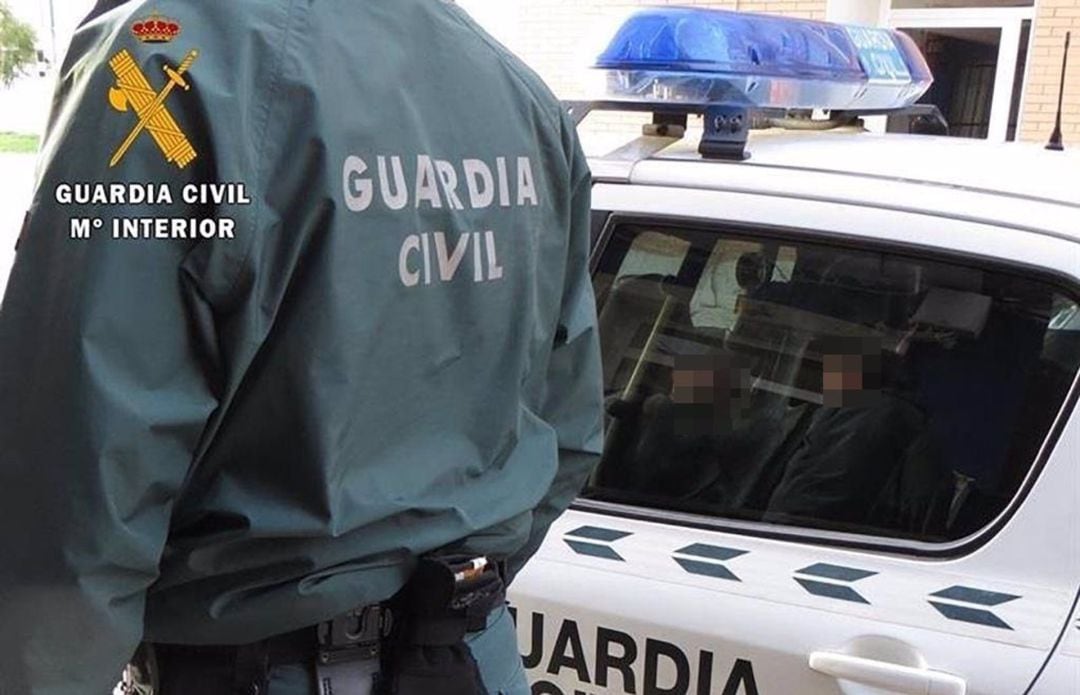 Un agente de la Guardia Civil junto a un coche patrulla