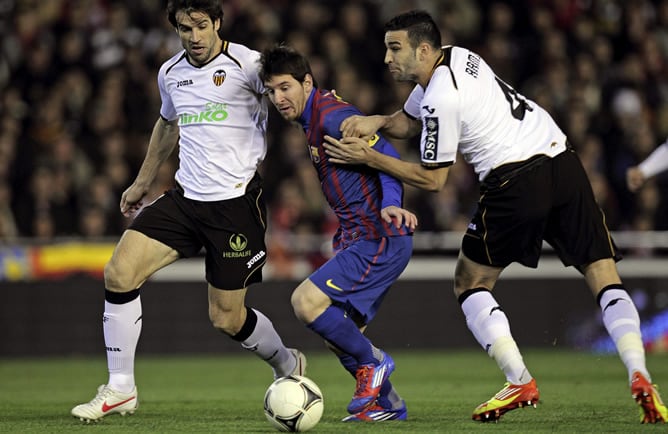 El delantero argentino del Barcelona Lionel Messi intenta superar a los jugadores del Valencia Davi Albelda  y Adil Rami durante el partido correspondiente a la ida de las semifinales de la Copa del Rey