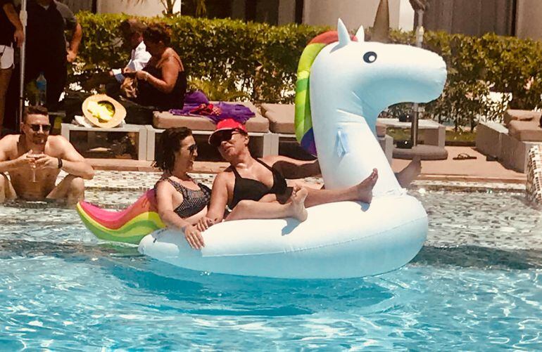 Dos chicas se divierten en la piscina con un flotador de unicornio.