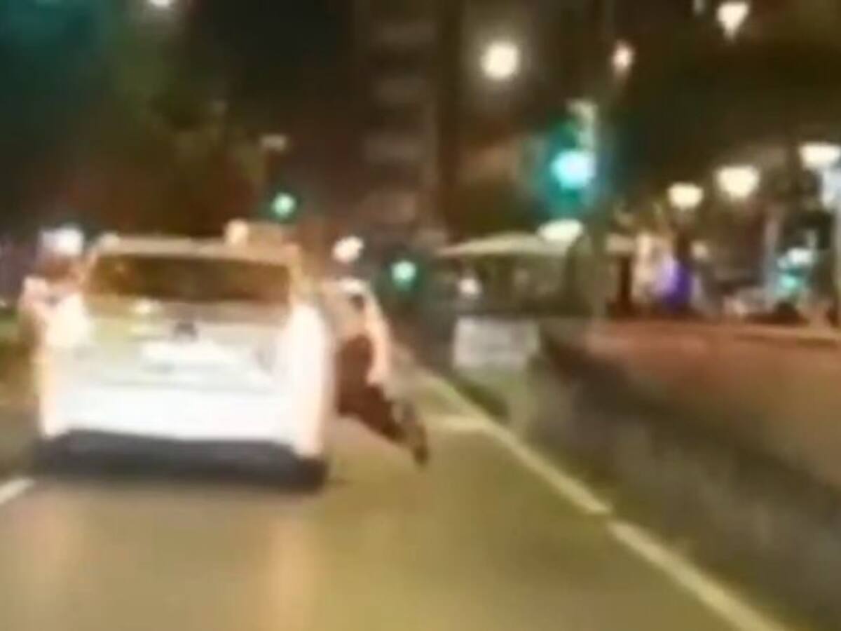Un taxi circula por Gijón con un hombre colgado de la ventanilla