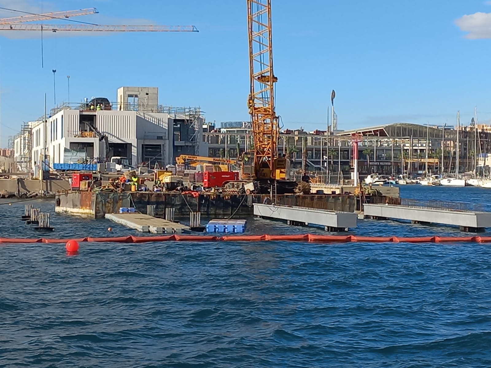 Una plataforma flotante con la grúa que mueve las estructuras para la isla de la bocana del puerto de Alicante