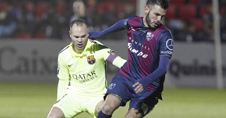 El centrocampista del Huesca, Iñigo Ros , controla el balón ante el jugador del F. C. Barcelona, Andrés Iniesta.