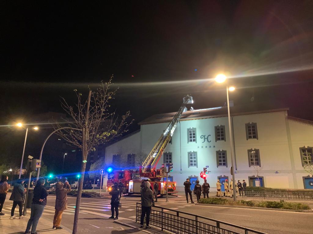 Los bomberos despliegan una escala para desalojar del tejado del antiguo hotel a dos personas