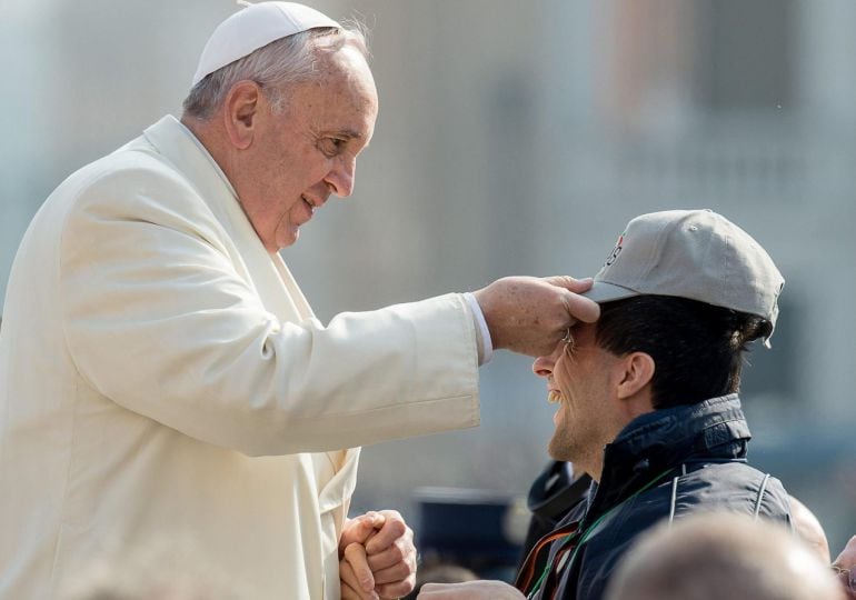 VAT02 CIUDAD DEL VATICANO (VATICANO), 11/03/2015.- Fotografía facilitada por el L&#039;Osservatore Romano que muestra al papa Francisco poniendo la gorra a un hombre antes de la audiencia semanal del papa en la Plaza de San Pedro en el Vaticano, hoy 11 de marz